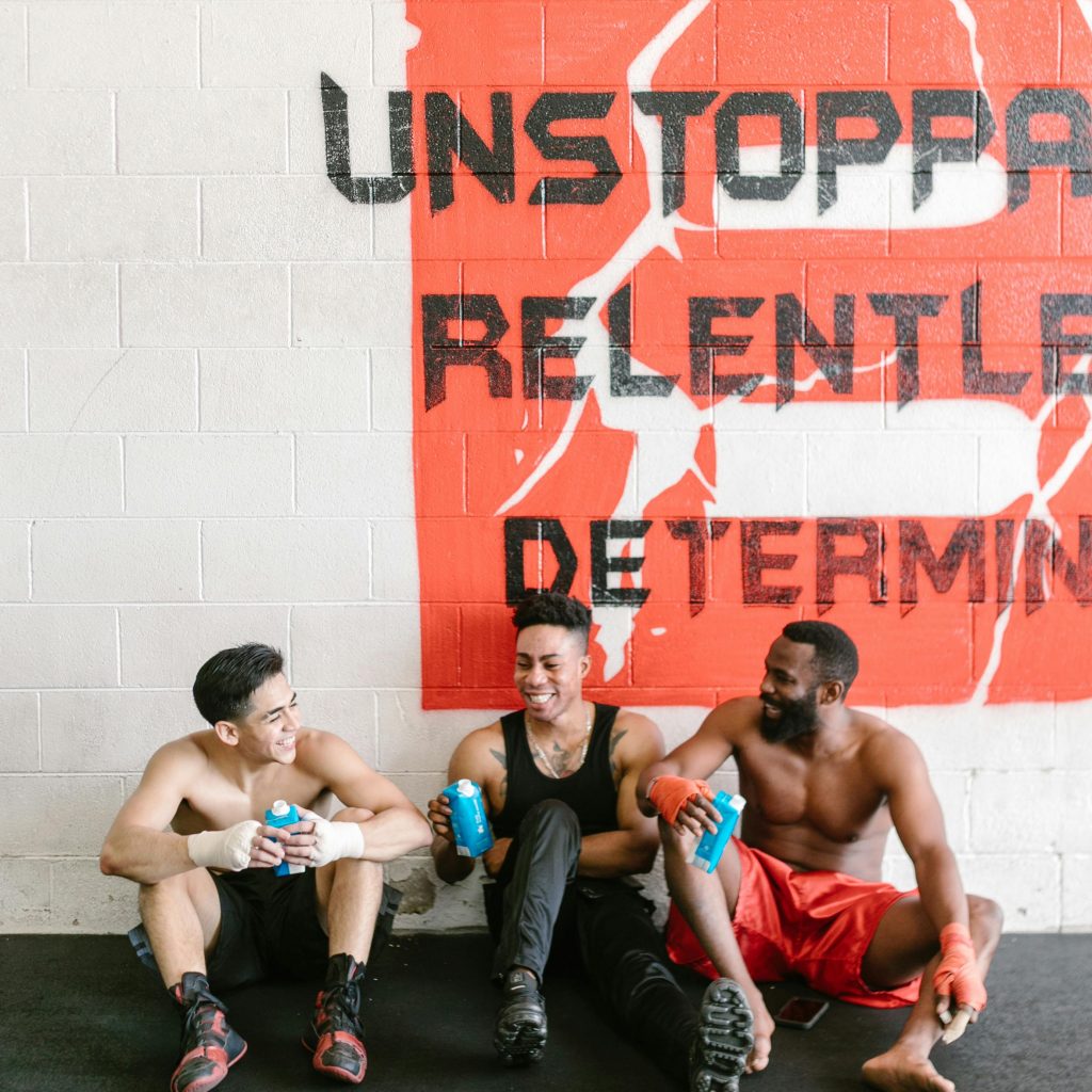 three gym members sitting on the floor talking to each other