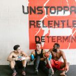 three gym members sitting on the floor talking to each other