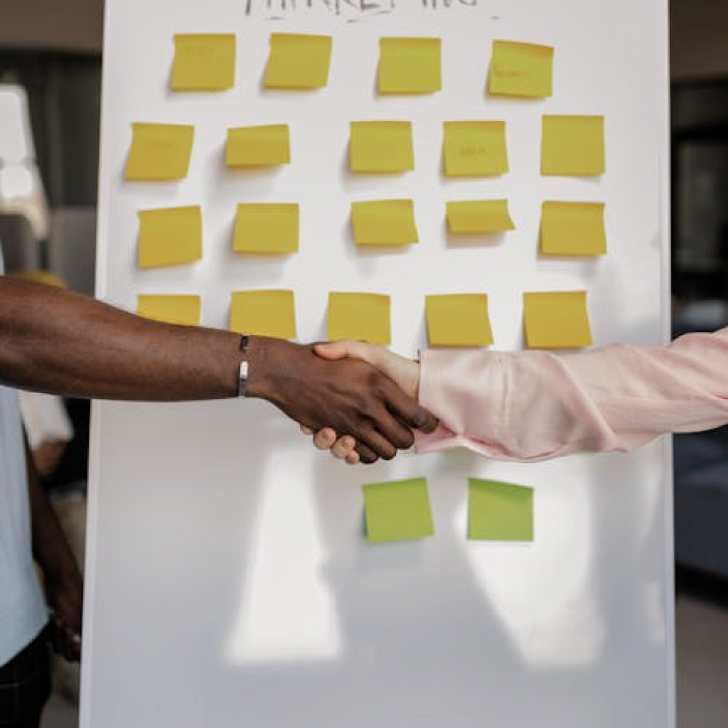 two people shaking hands in front of a board with a marketing label