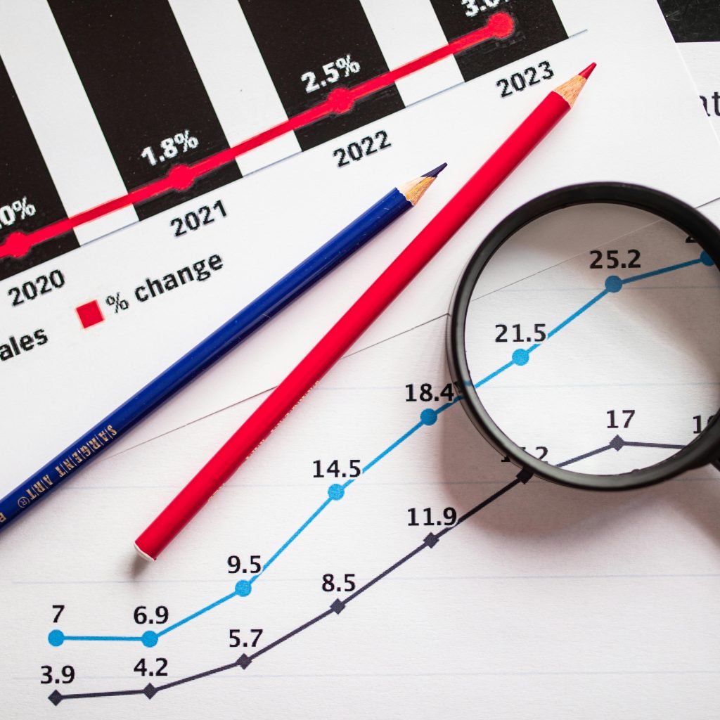 colored pencils and a magnifying glass over documents with graphs