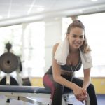 a happy gym member sitting on a bench with earphones in