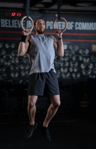 A man doing pull ups in front of a fitness center mission statement