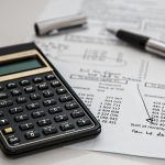calculator, pen, and a written budget